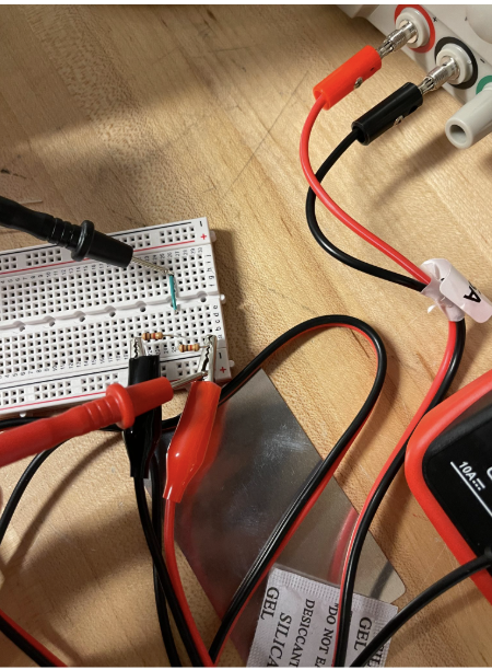 Close-up of a breadboard voltage divider circuit with test leads
